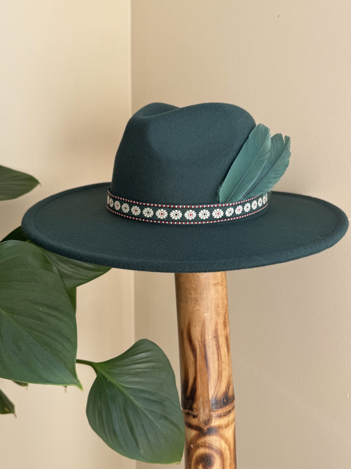 Forest green fedora with pale beaded band and feather