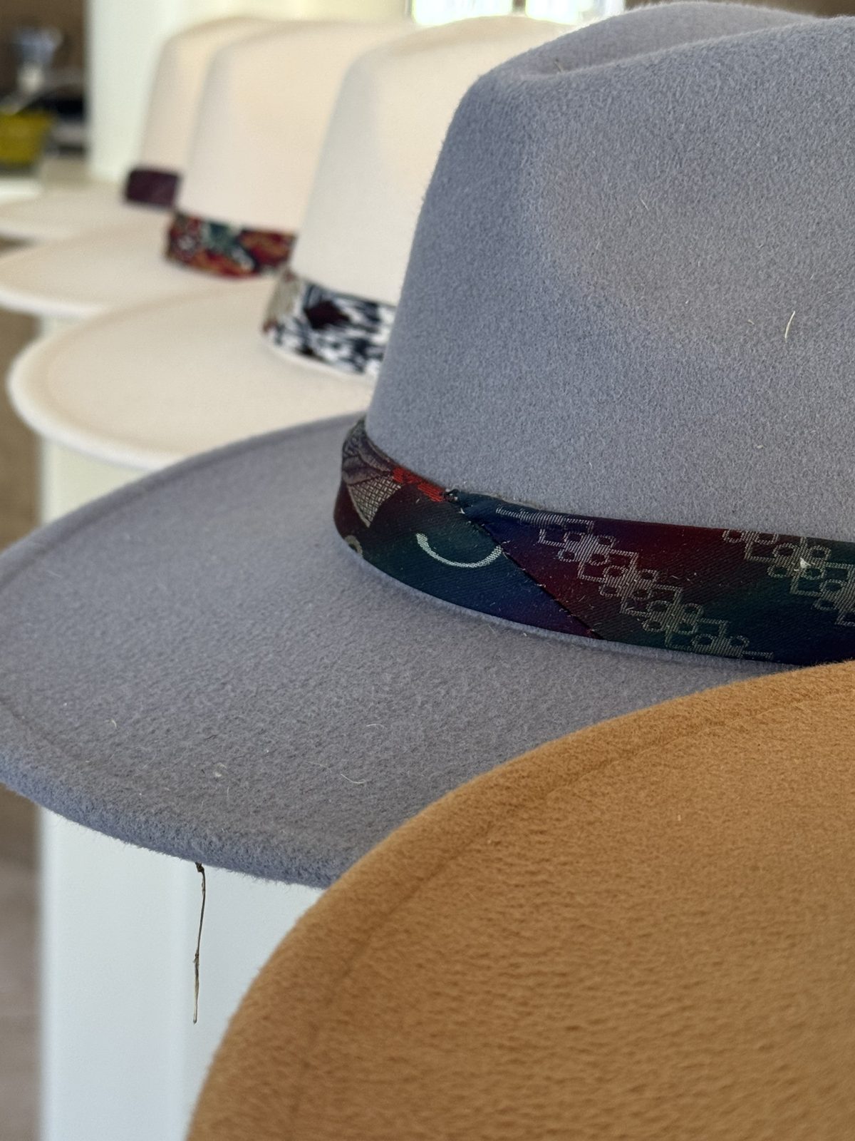 Row of felt fedoras in grey, blue and camel