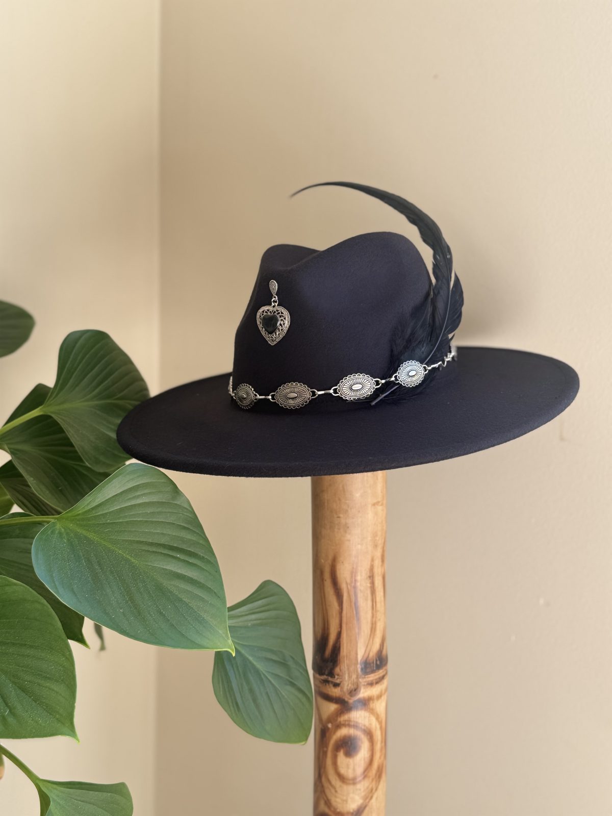 Black fedora with heart pendant and feather