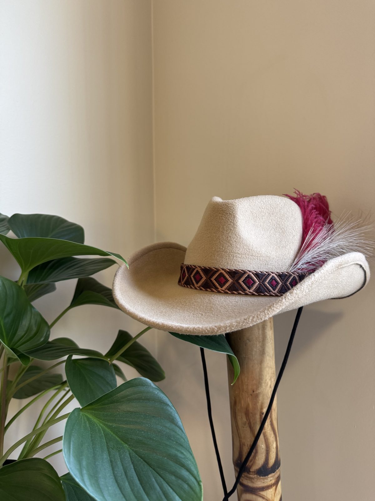 Cream fedora with dark band and red feather