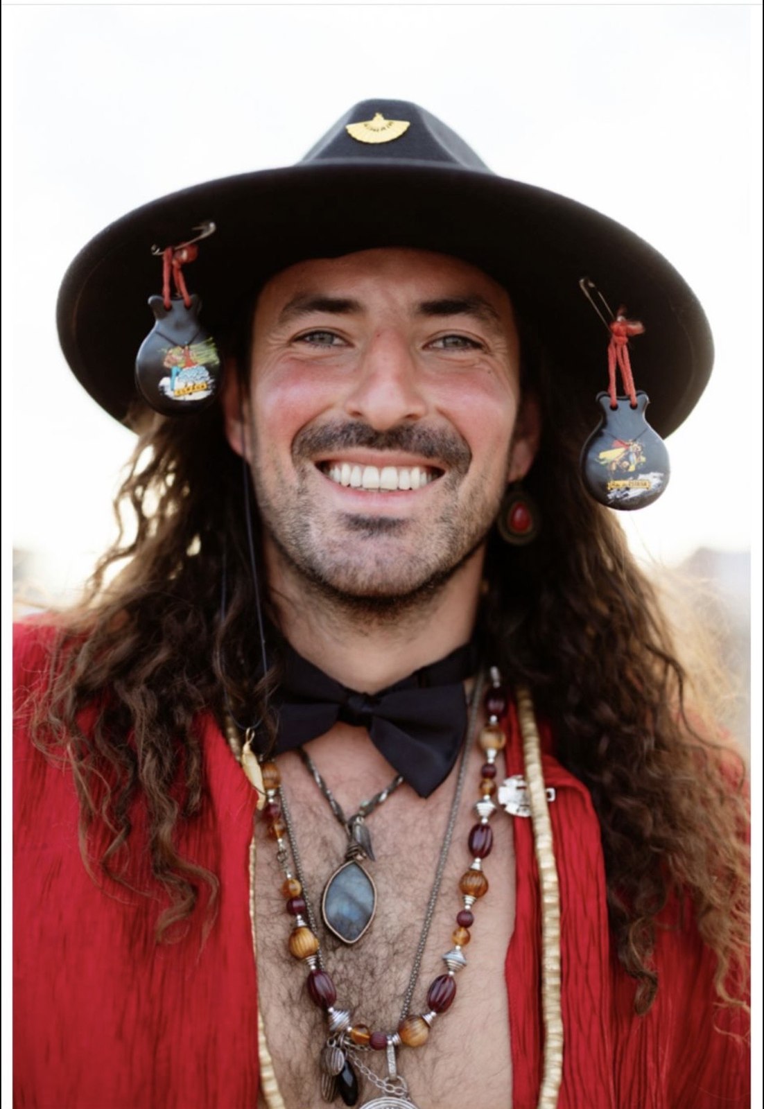 Man smiling wearing a black fedora with charms
